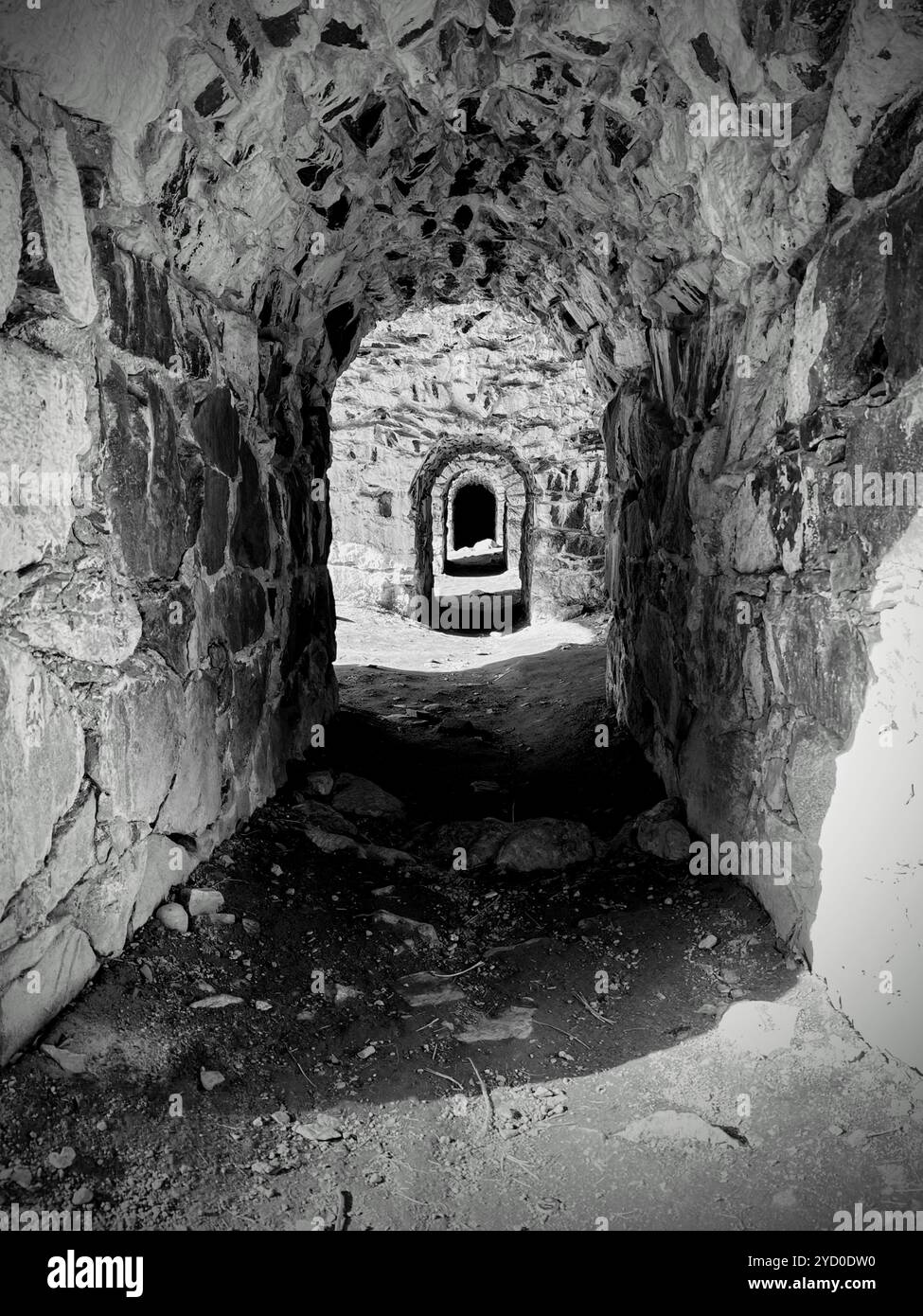 A shadowy, winding stone corridor with layered arches, creating a haunting visual of endless darkness. - Smartphone Captured Stock Image