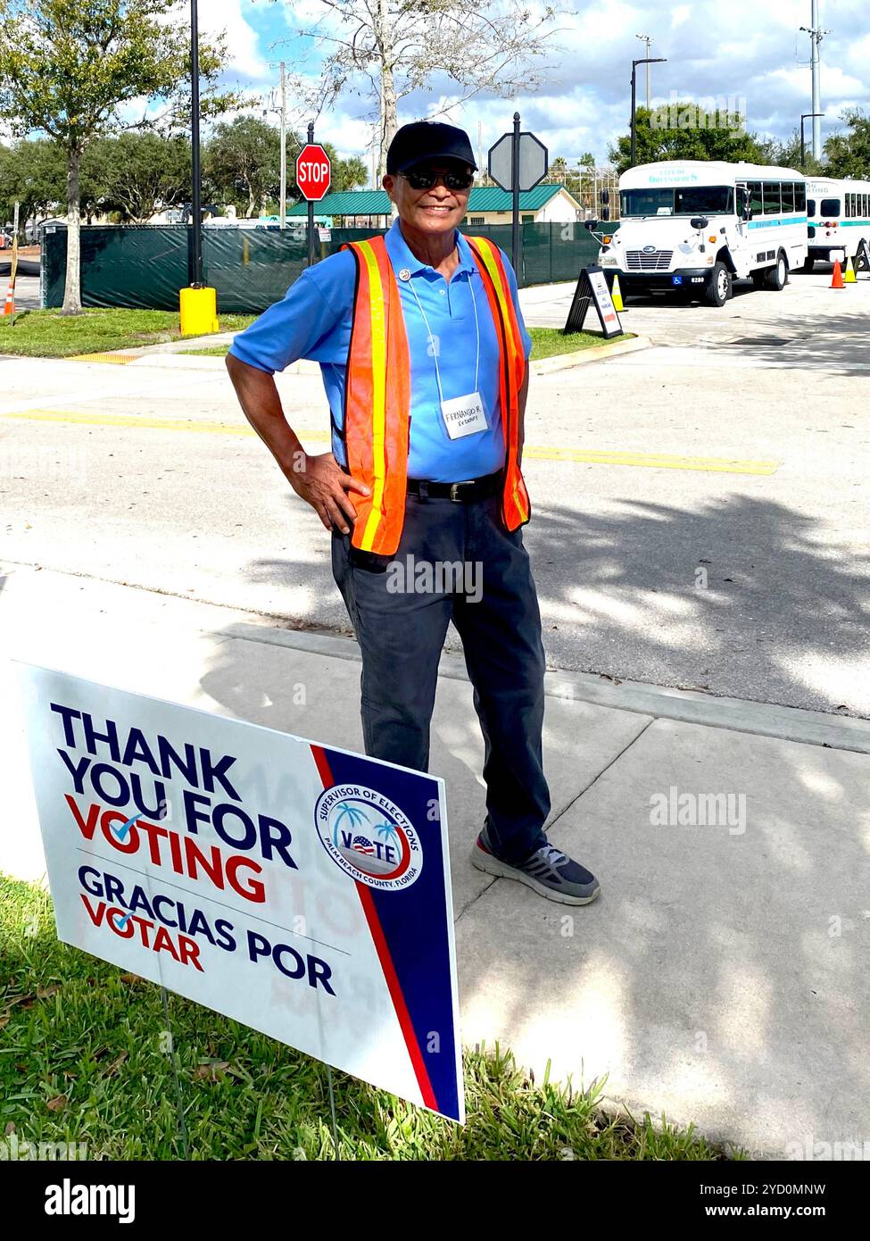 Volunteer at an Early Voting location in Palm Beach County, FL. October 22, 2024, standing by bi-lingual signage in Spanish and English. - Smartphone Captured Stock Image
