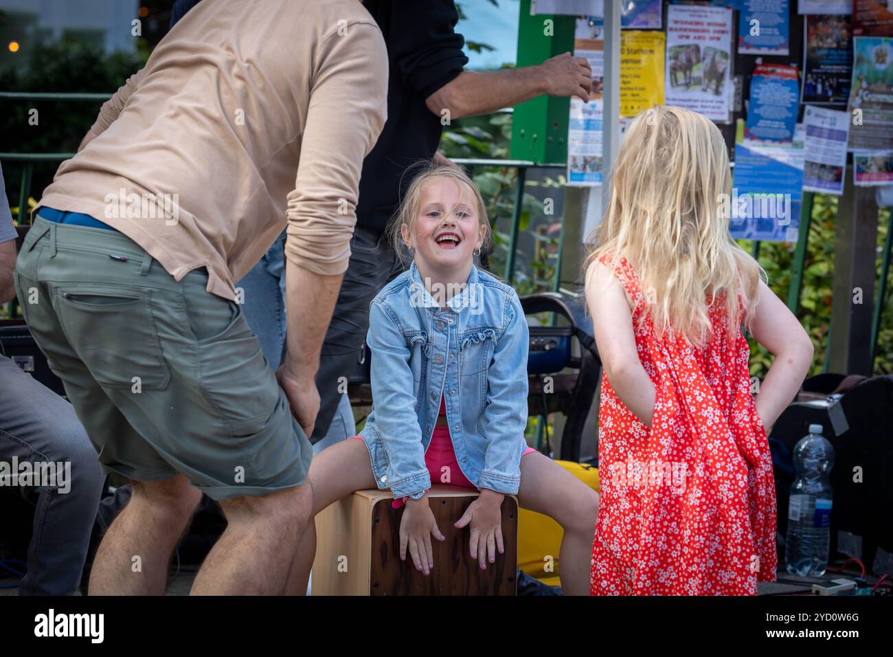 Lymm Food Festival 2024 - Young girl in denim jacket sits on a Cajon and tries to make music Stock Photo