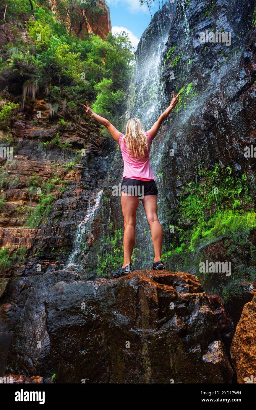 Woman stands on rock in front of cascading waterfall Stock Photo - Alamy