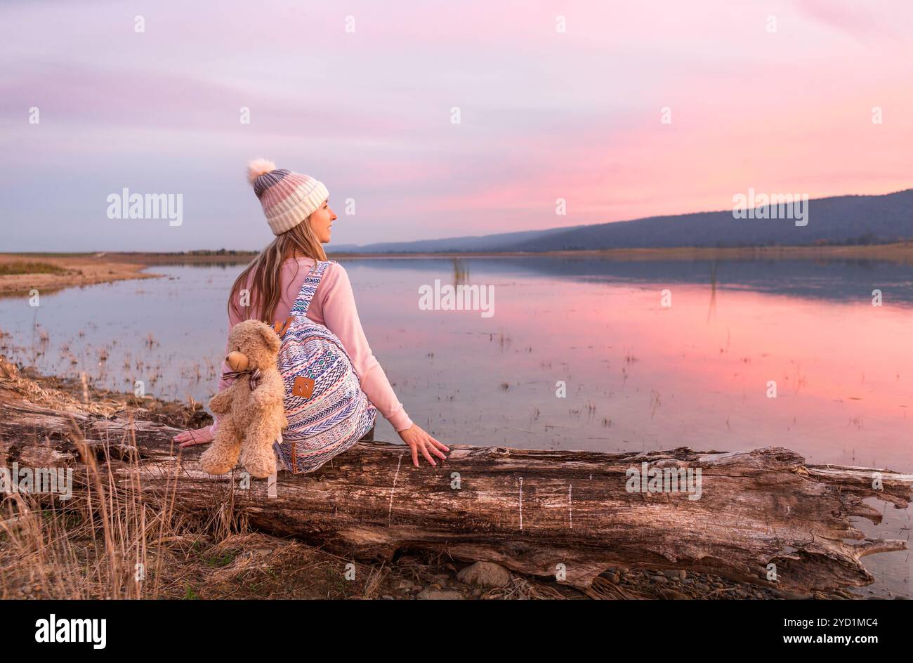 Relaxed woman watching a serene sunset by the lake Stock Photo