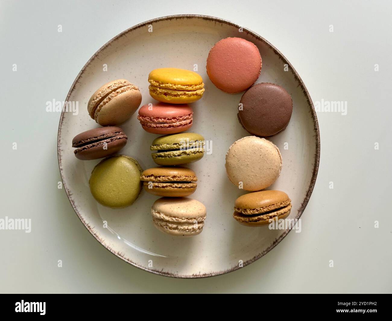 Macarons in different colors and tastes on the beige plate on the white background - Smartphone Captured Stock Image