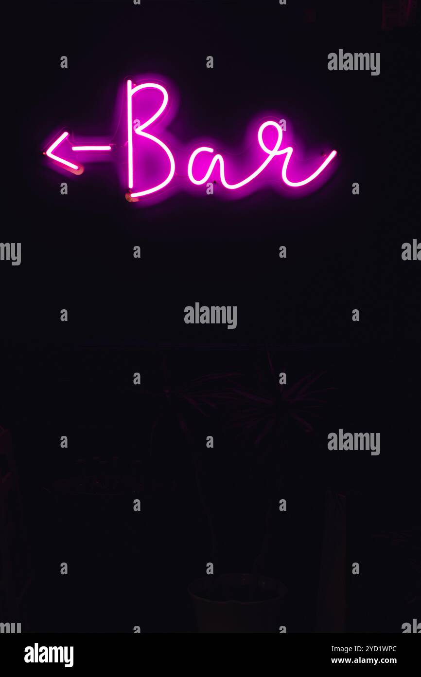 magenta pink neon bar sign against black wall at night Stock Photo