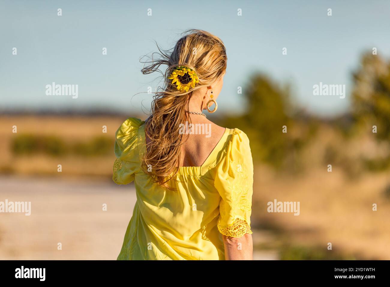 Woman outdoors in sunshine sunflower in her wavy hair Stock Photo - Alamy