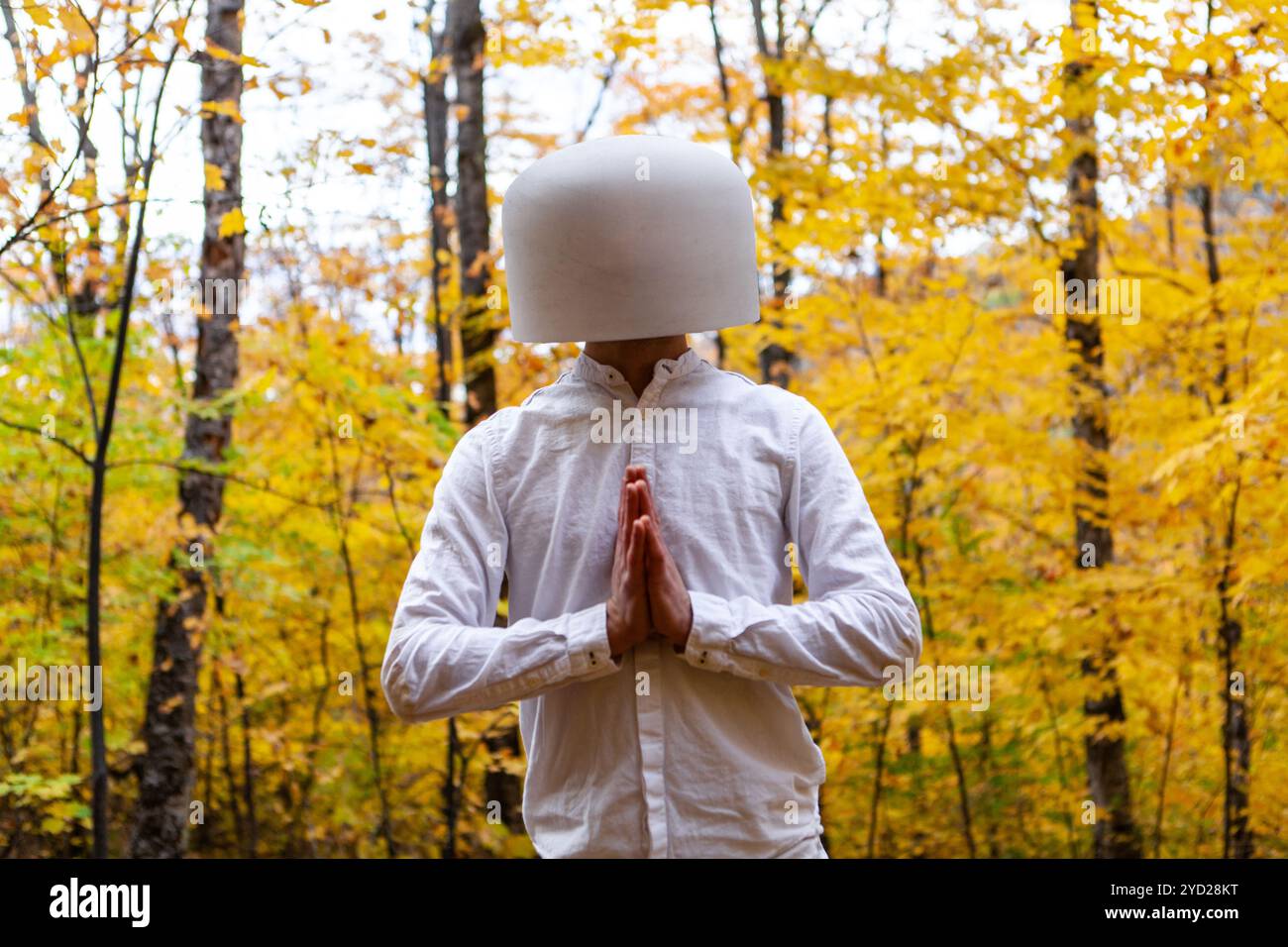 Man in white has a crystal bowl on his head while showing thankfulness Stock Photo