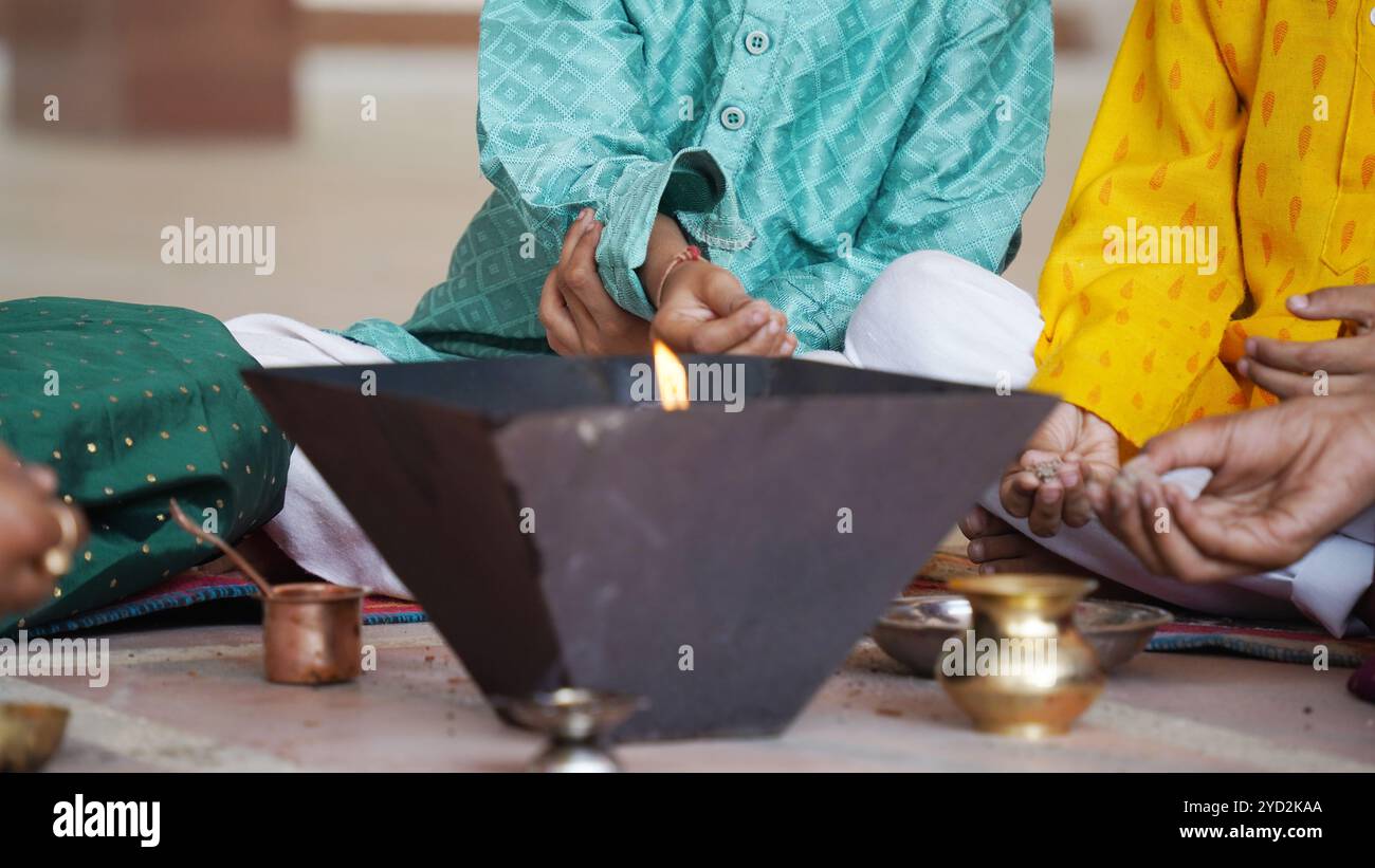 A Hindu family gathers around a sacred fire for Yagya during a festival celebration. The Havan and pooja rituals include offerings and Vedic mantras Stock Photo