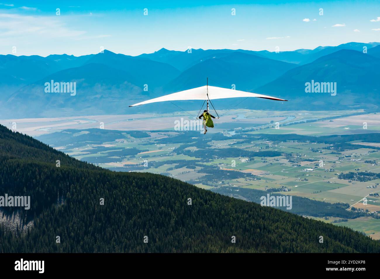 Hang gliding over valley farmlands and mountains Stock Photo