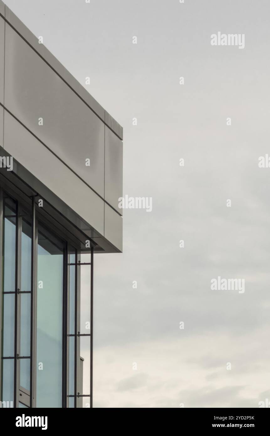 The corner of a modern office building with a cloudy sky background ...