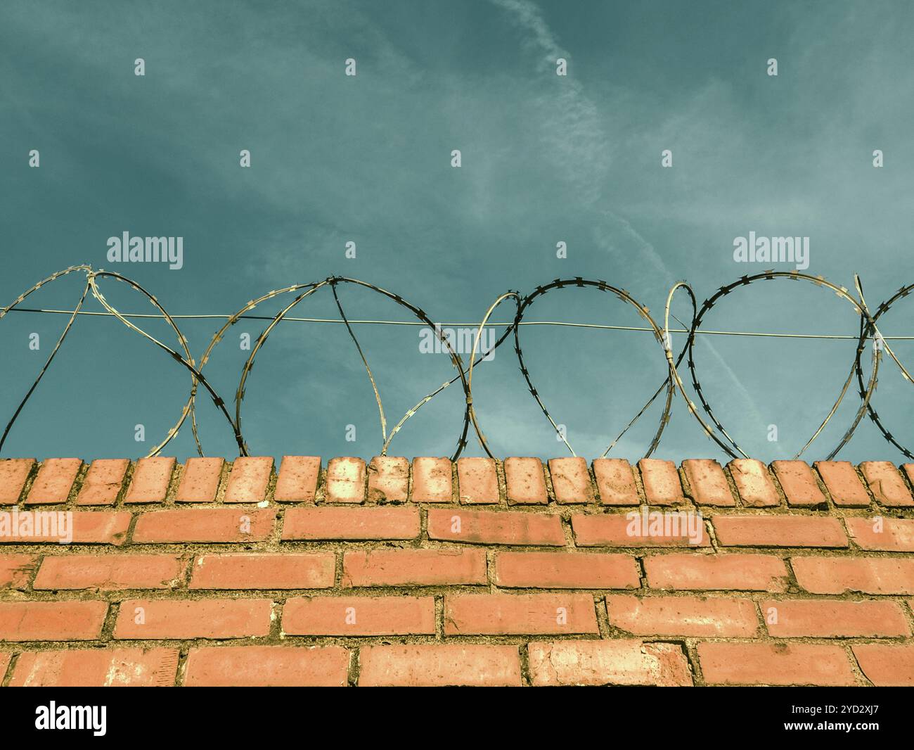 Barbed Or Razor Wire On Top Of A Red Brick Wall Around Private Property Stock Photo