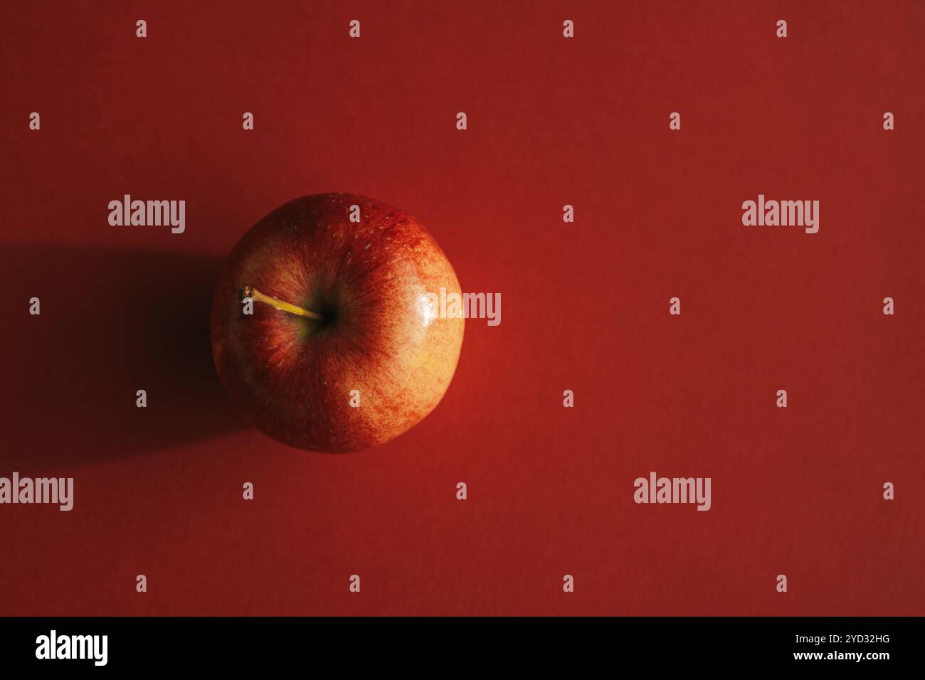 Red apple forming a shadow against red backround Stock Photo