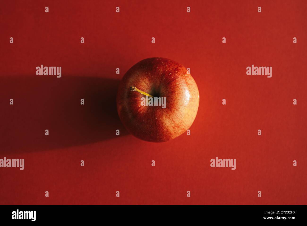 Red apple forming a shadow against red backround Stock Photo