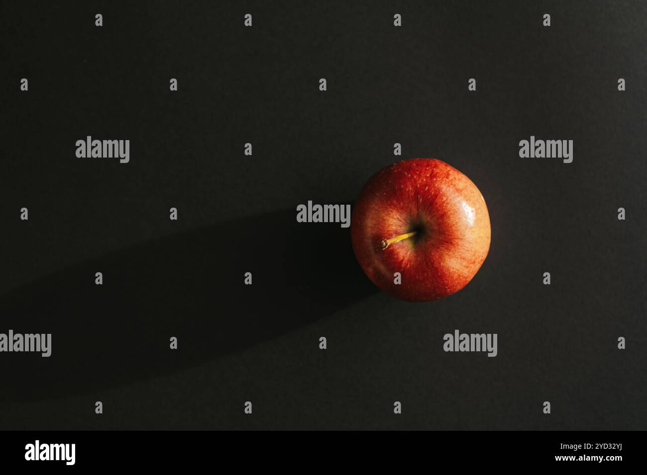 Red apple forming a shadow against black backround Stock Photo