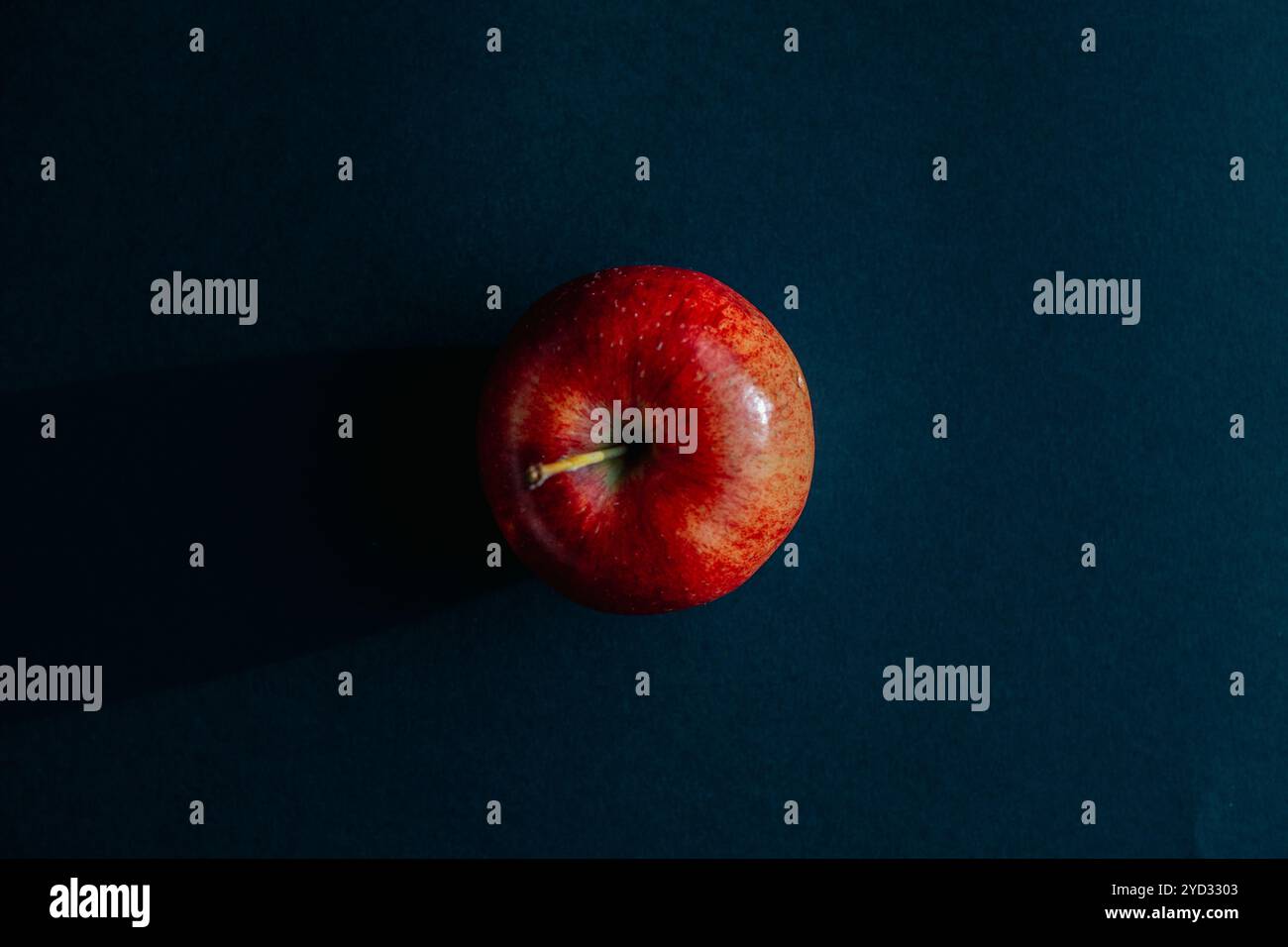 Red apple forming a shadow against black backround Stock Photo