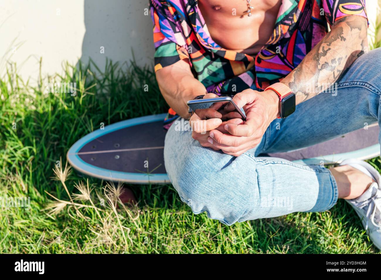 unrecognizable male sitting on skate using phone Stock Photo