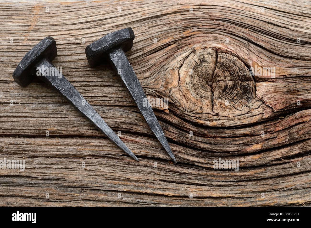 Two forged nails on a wooden background Stock Photo