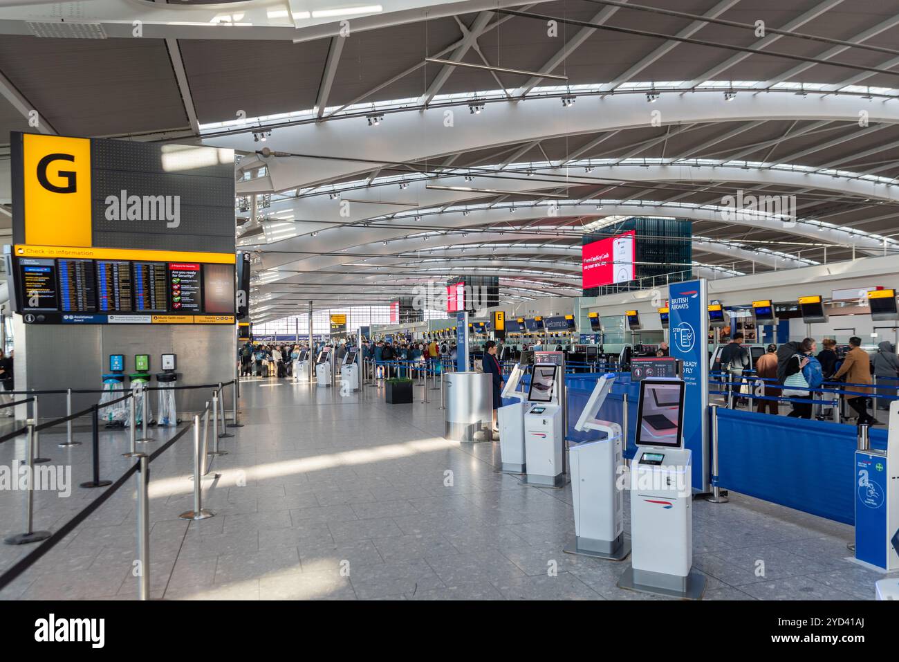 Inside Terminal 5 departures at London Heathrow Airport, UK. Passengers queuing at bag check-in for British Airways flights. Zone G Stock Photo