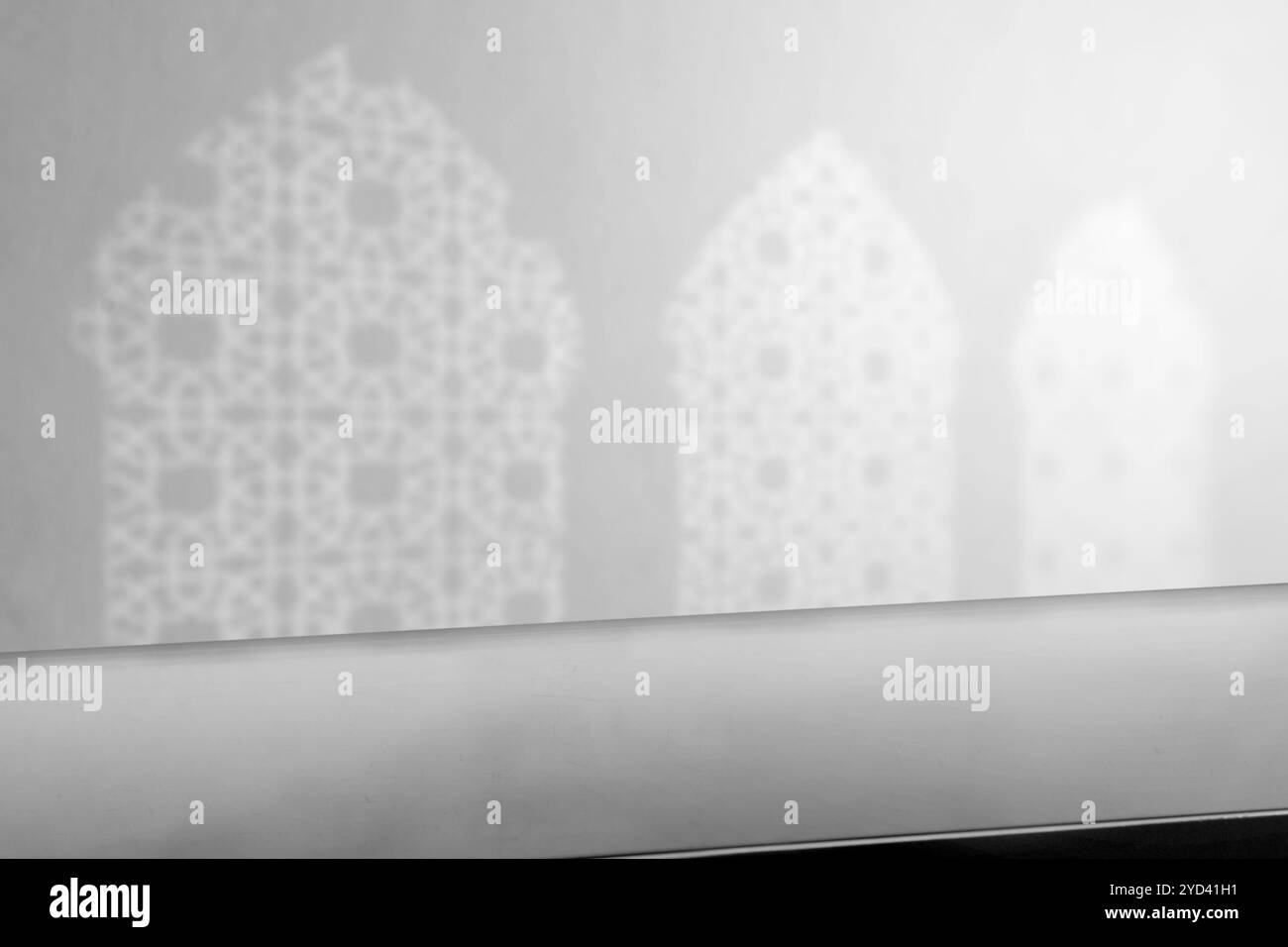 Empty table top with white shadow of three arched mosque windows on the ...
