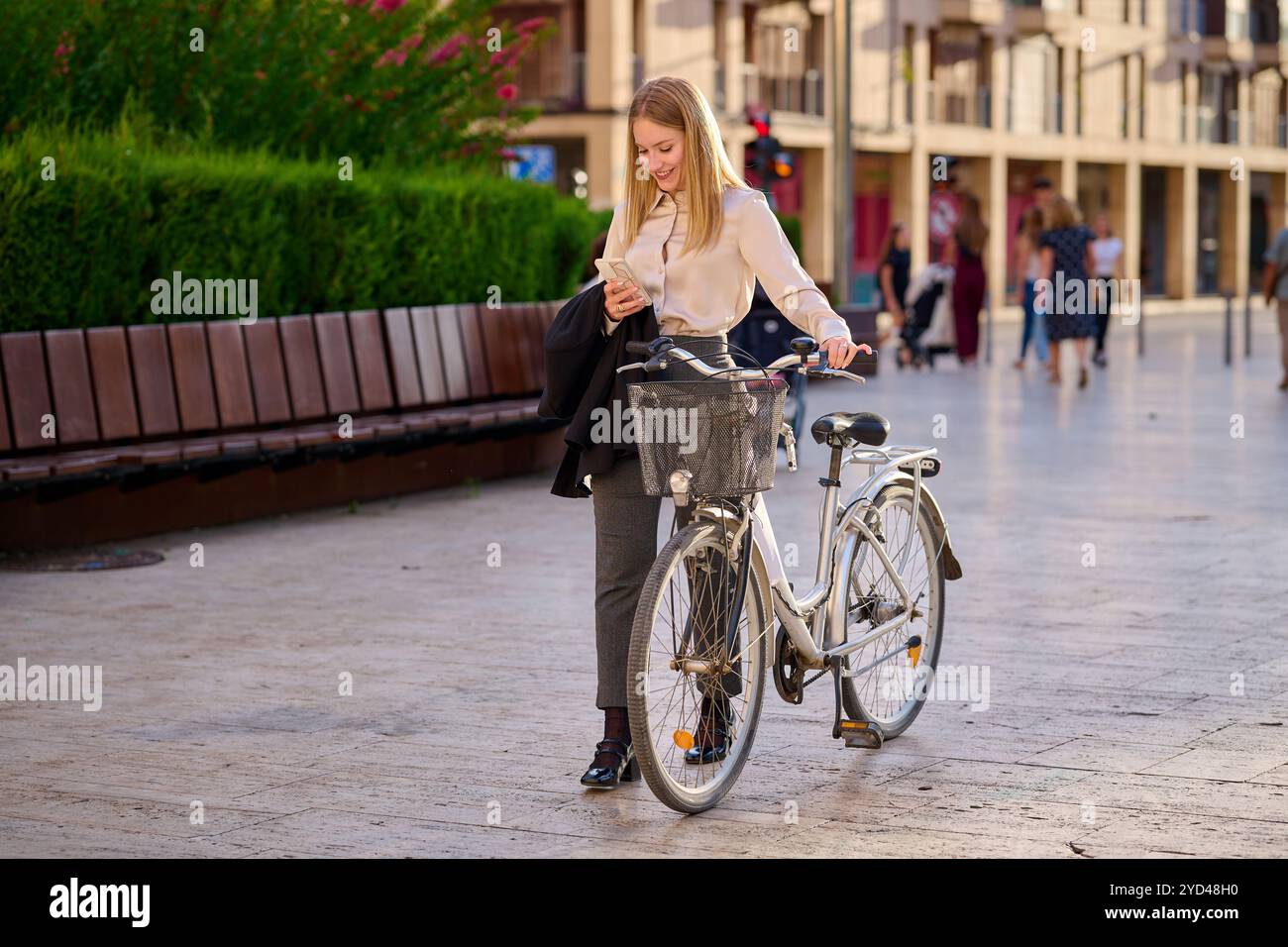 Young woman checking her phone while standing beside a bicycle Stock Photo