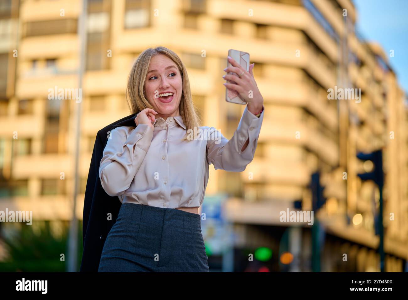 Young woman taking a selfie on a city street during sunset Stock Photo