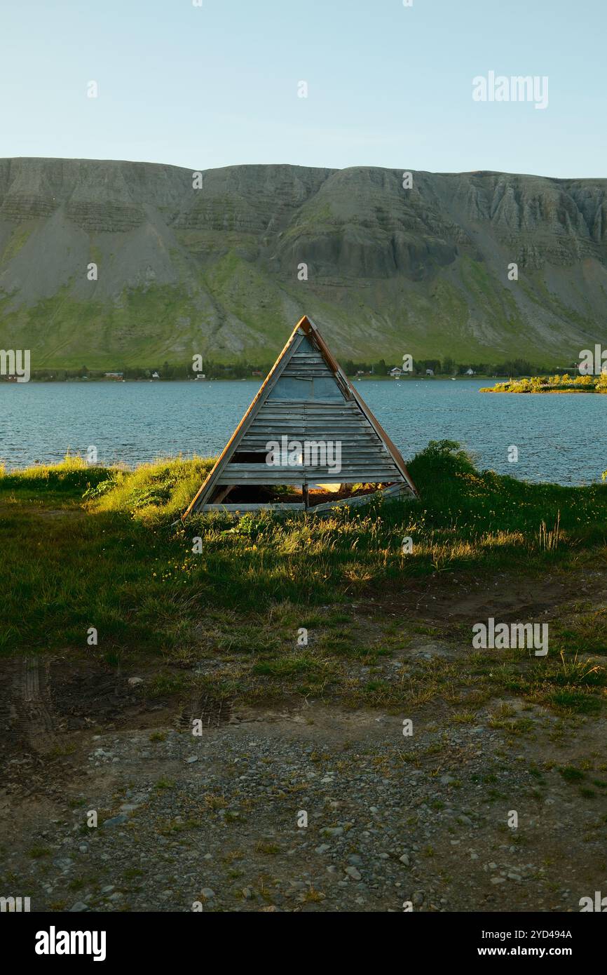 Old wooden shed on green shore of cold lake Stock Photo