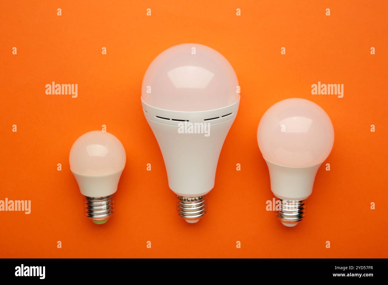Comparison of different light bulbs on orange background. Top view Stock Photo
