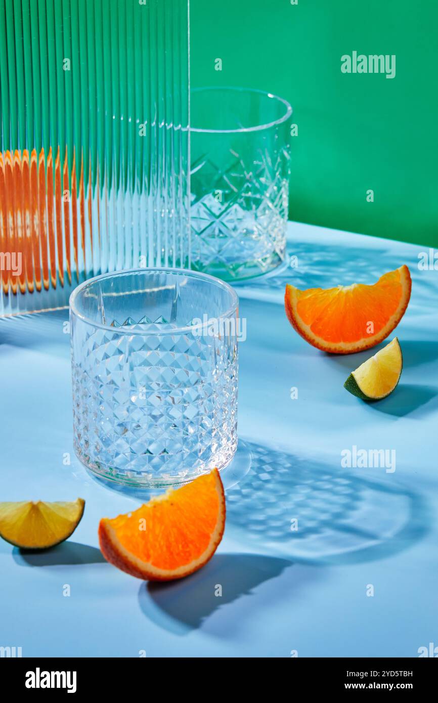Two empty glass glasses on colored backgrounds with shadows from sunlight Stock Photo