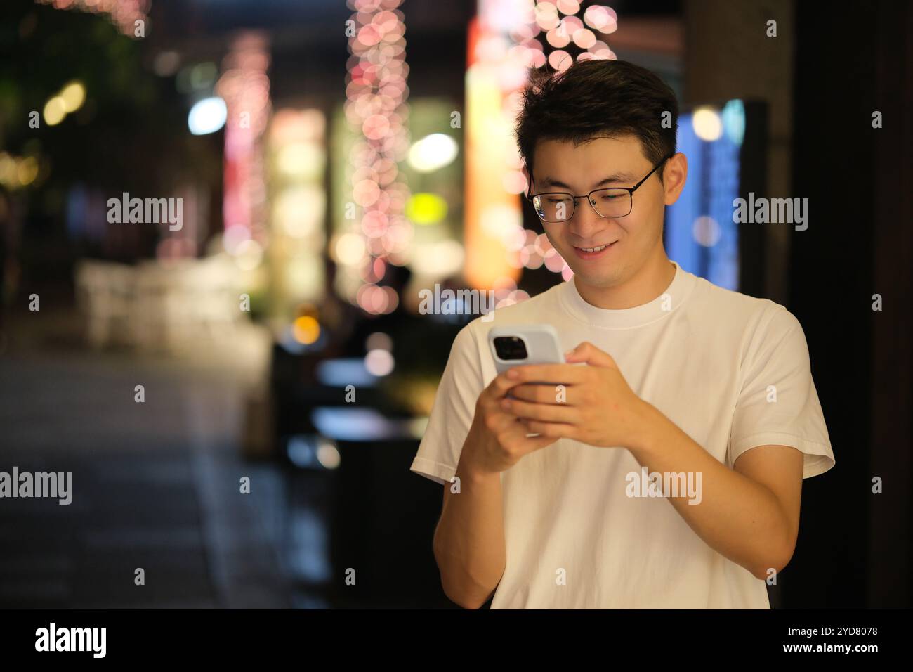 Asian young man text messaging on phone at night Stock Photo