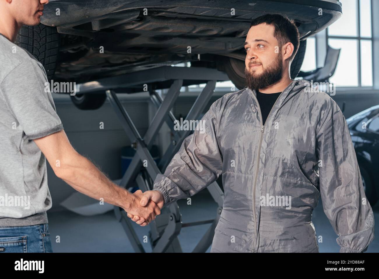 Mechanic shaking hands with car owner in the workshop garage. Car auto services concept Stock Photo