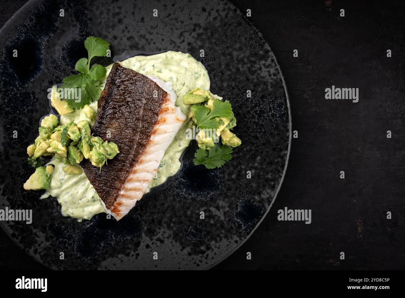 Fried skrei cod fish filet with mashed potato cream and avocado served ...