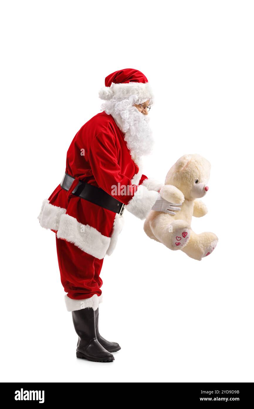 Full length profile shot of Santa Claus holding a teddy bear isolated ...