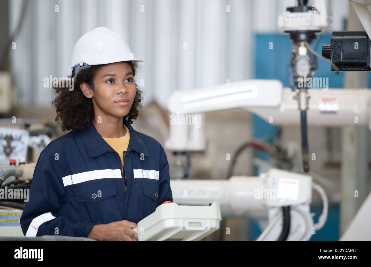 A young female worker is controlling a mechanical robot. Stock Photo