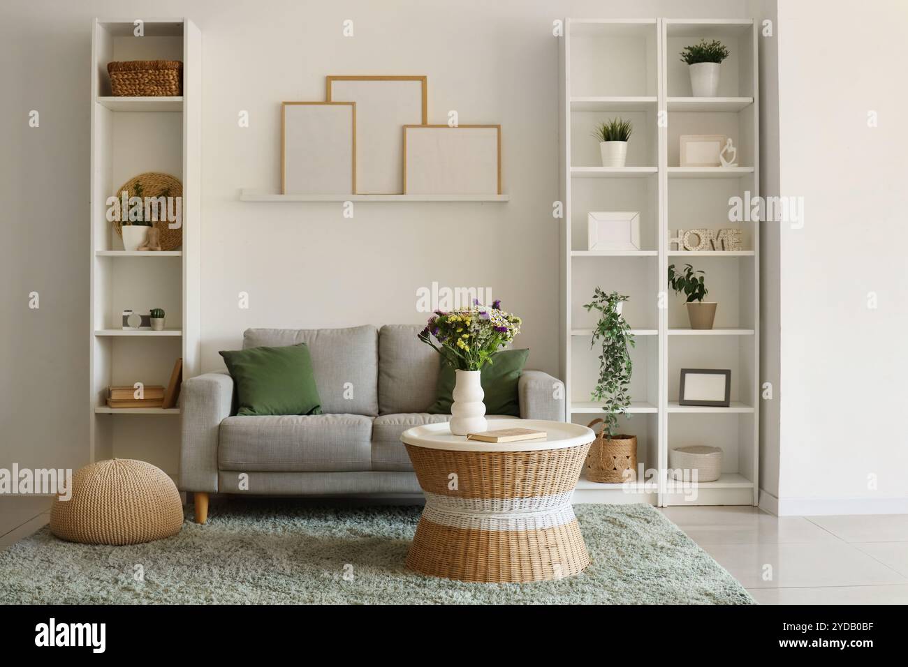 Cozy sofa and vase with wild flowers on coffee table in living room ...