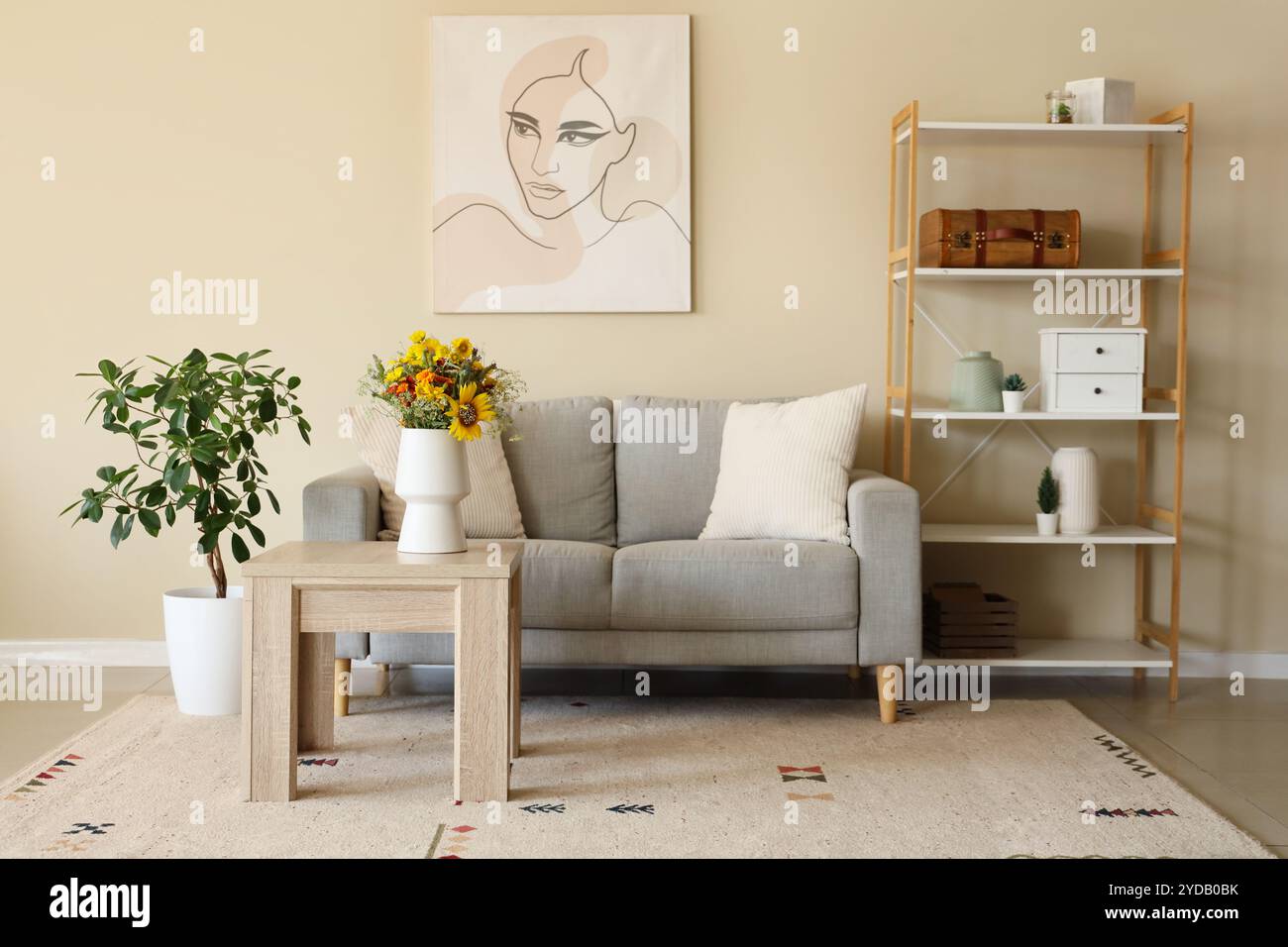 Cozy sofa and vase with wild flowers on coffee table in living room ...