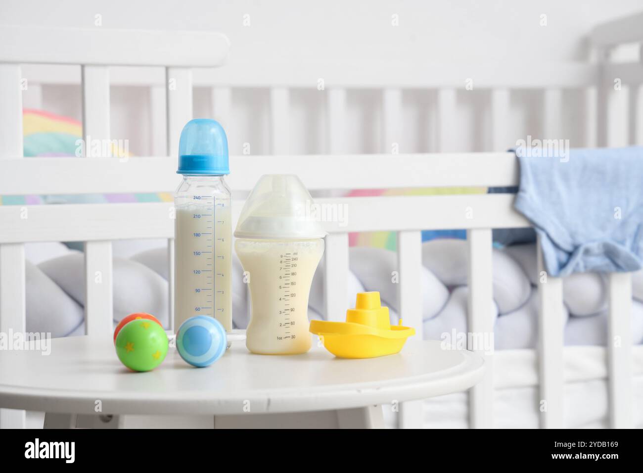 Bottles of baby milk formula, rattle and toy boat on light table near ...