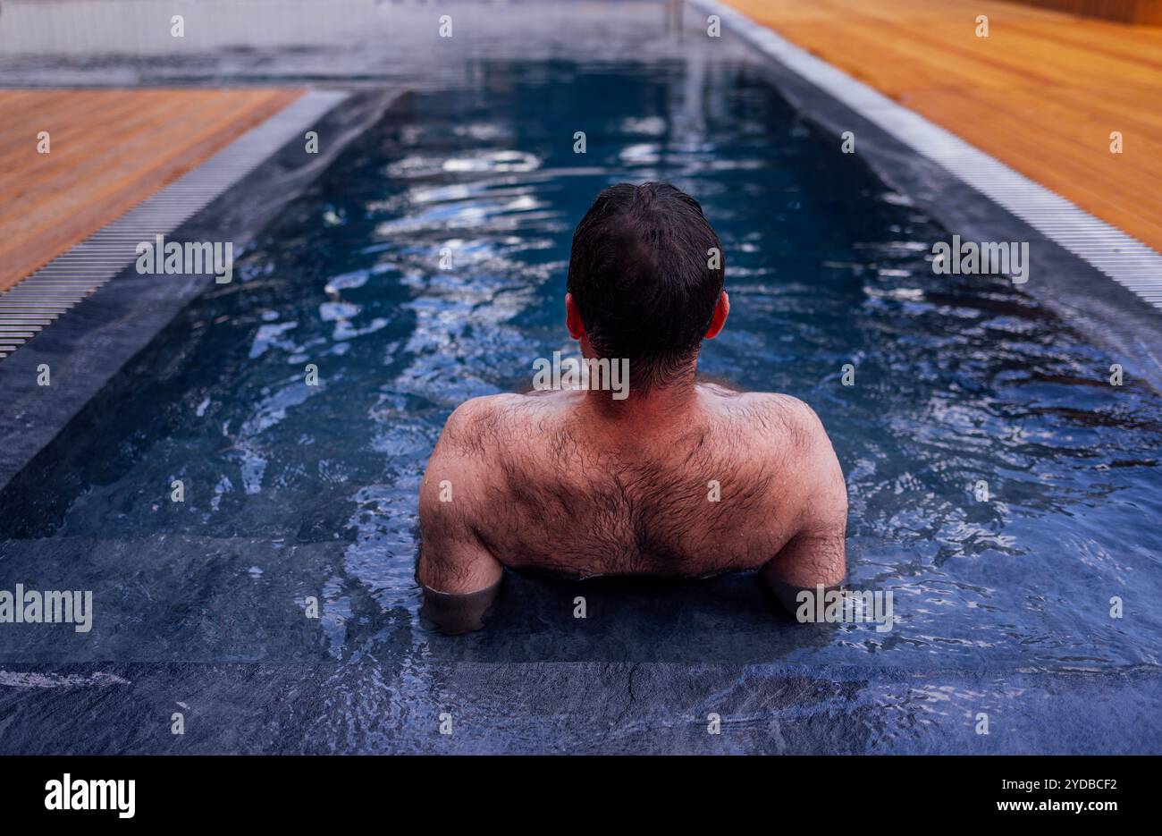A young attractive man is swimming in an indoor pool. A handsome guy is ...