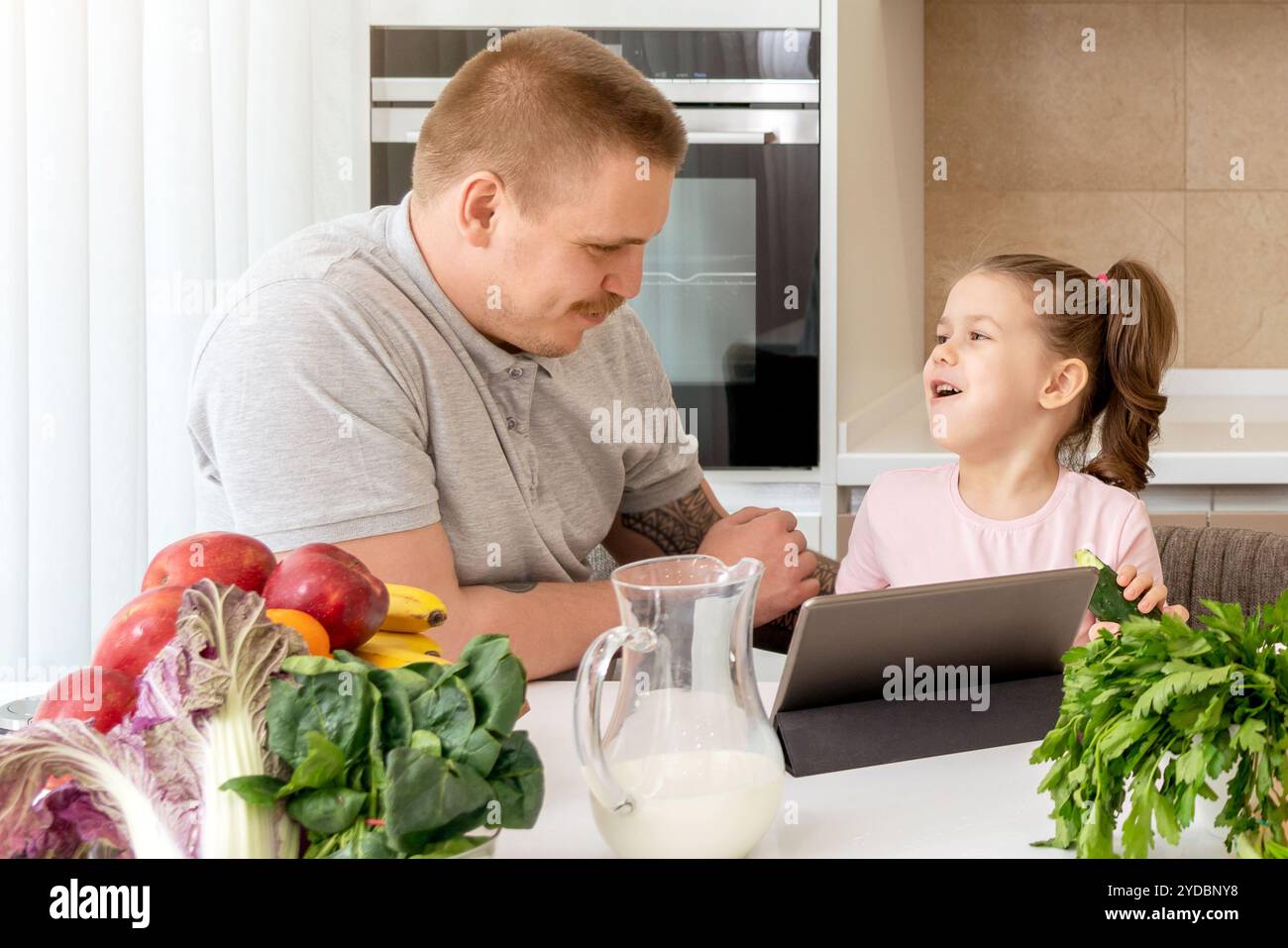 Father And Daughter Using Digital Tablet In Kitchen At Home Stock Photo
