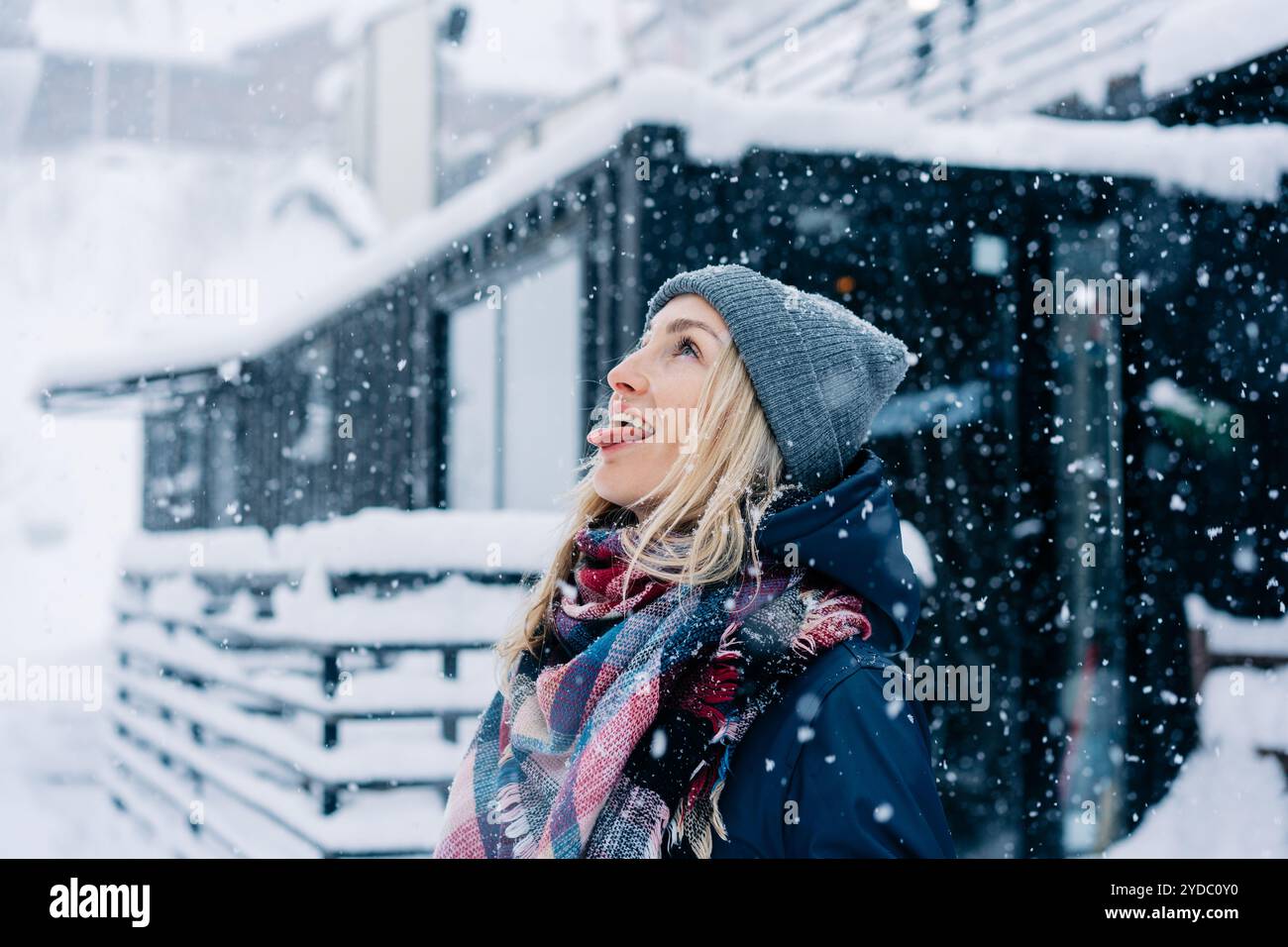 A young cheerful woman fools around like a child in a snowfall and ...