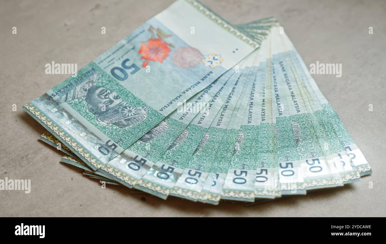 Malaysian ringgit banknotes fanned out on a concrete surface ...