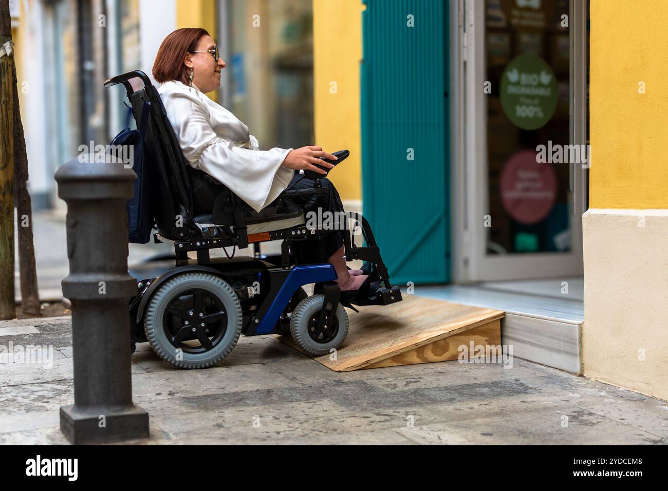 Woman in Electric Wheelchair Using Ramp to Access Store Stock Photo - Alamy