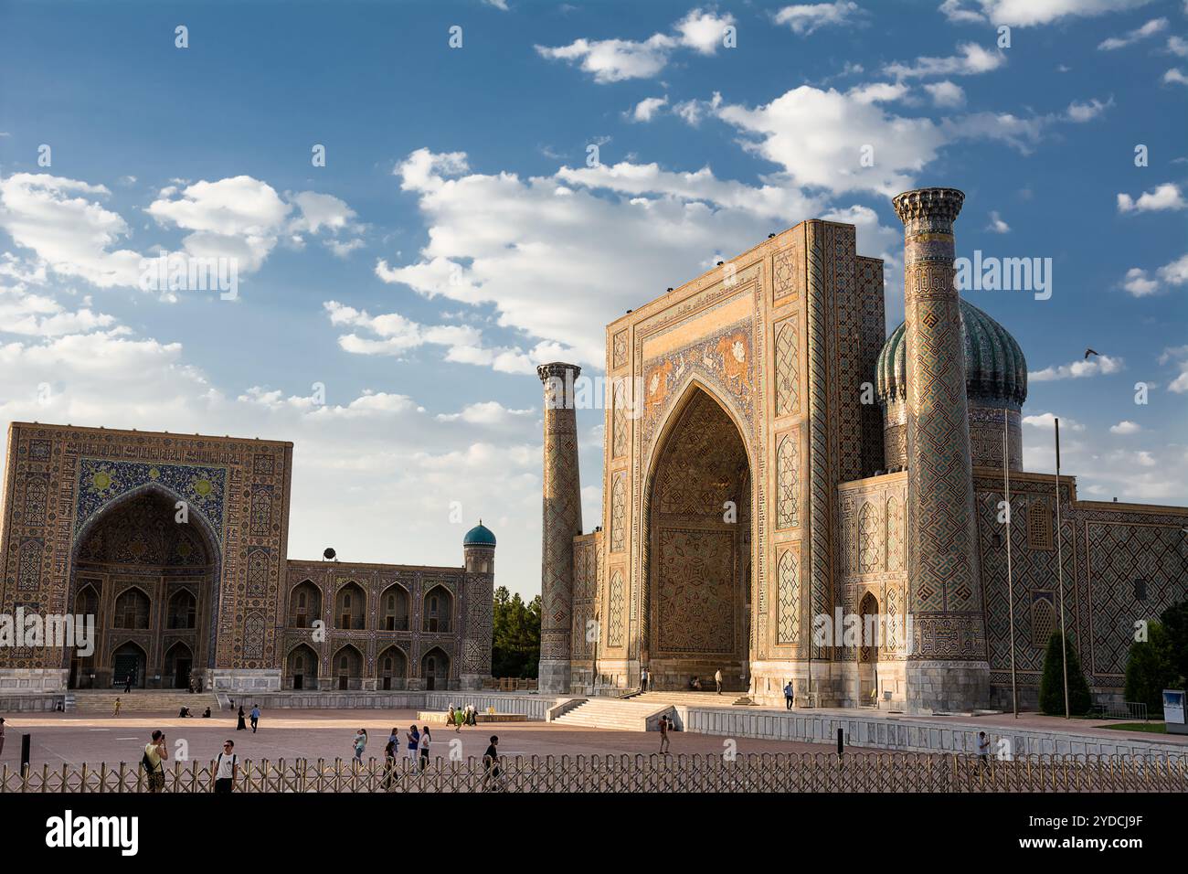 Samarkand, Uzbekistan - 05 July 2024: Portal and columns in Ulug Beg and Sher-Dor madrassa in the Registan of Samarkand with flower garden at sunset Stock Photo