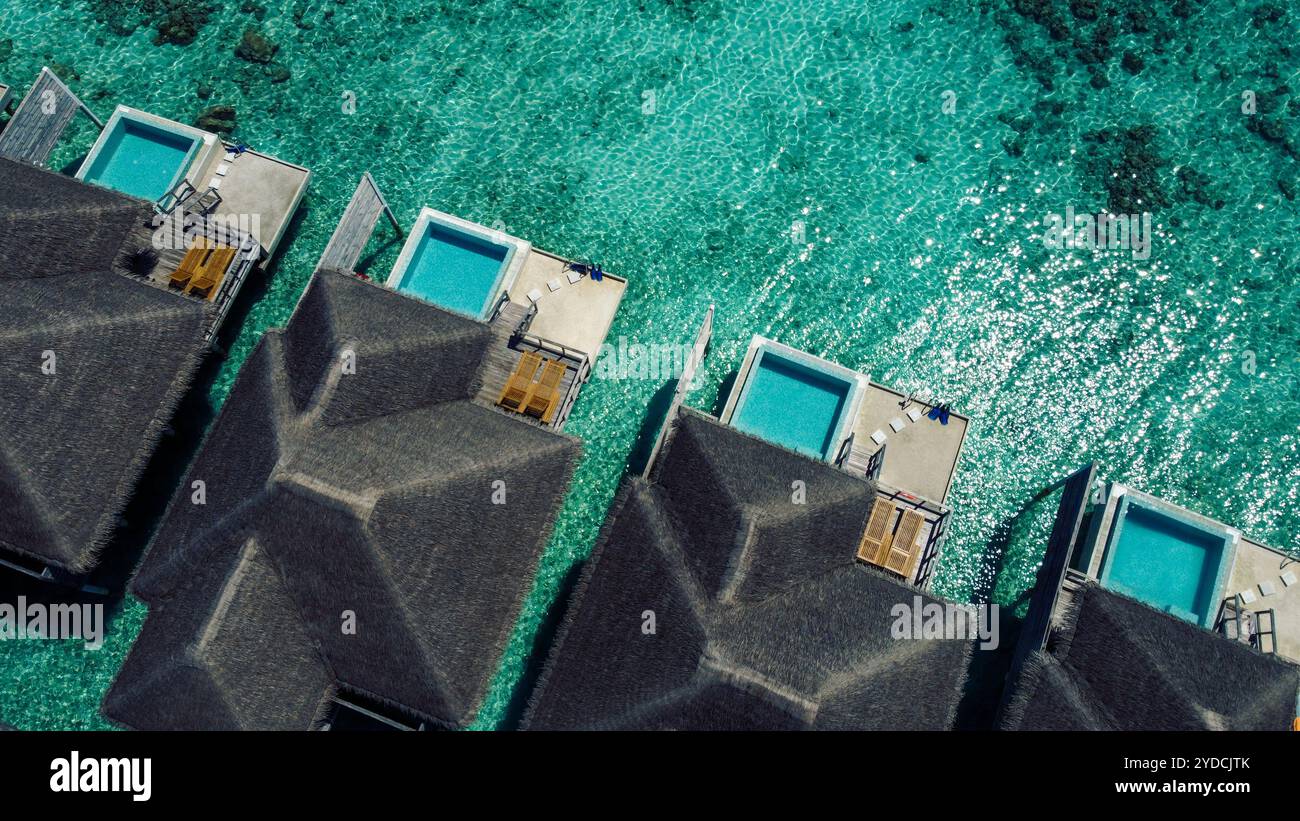 Aerial view of luxurious overwater villas with thatched roofs. The ...