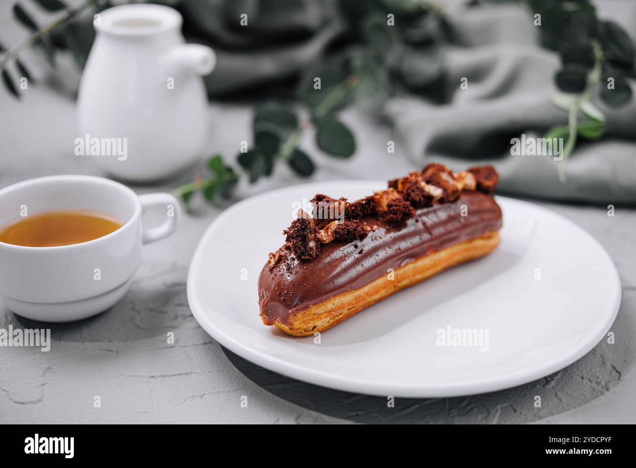 Eclair with Chocolate Cream and Hazelnuts and tea Stock Photo