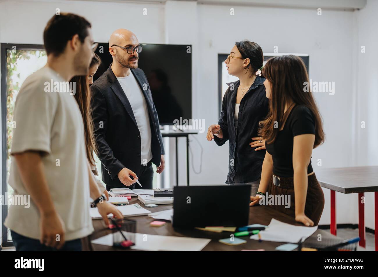 Students collaborating with professor on academic project in classroom setting Stock Photo