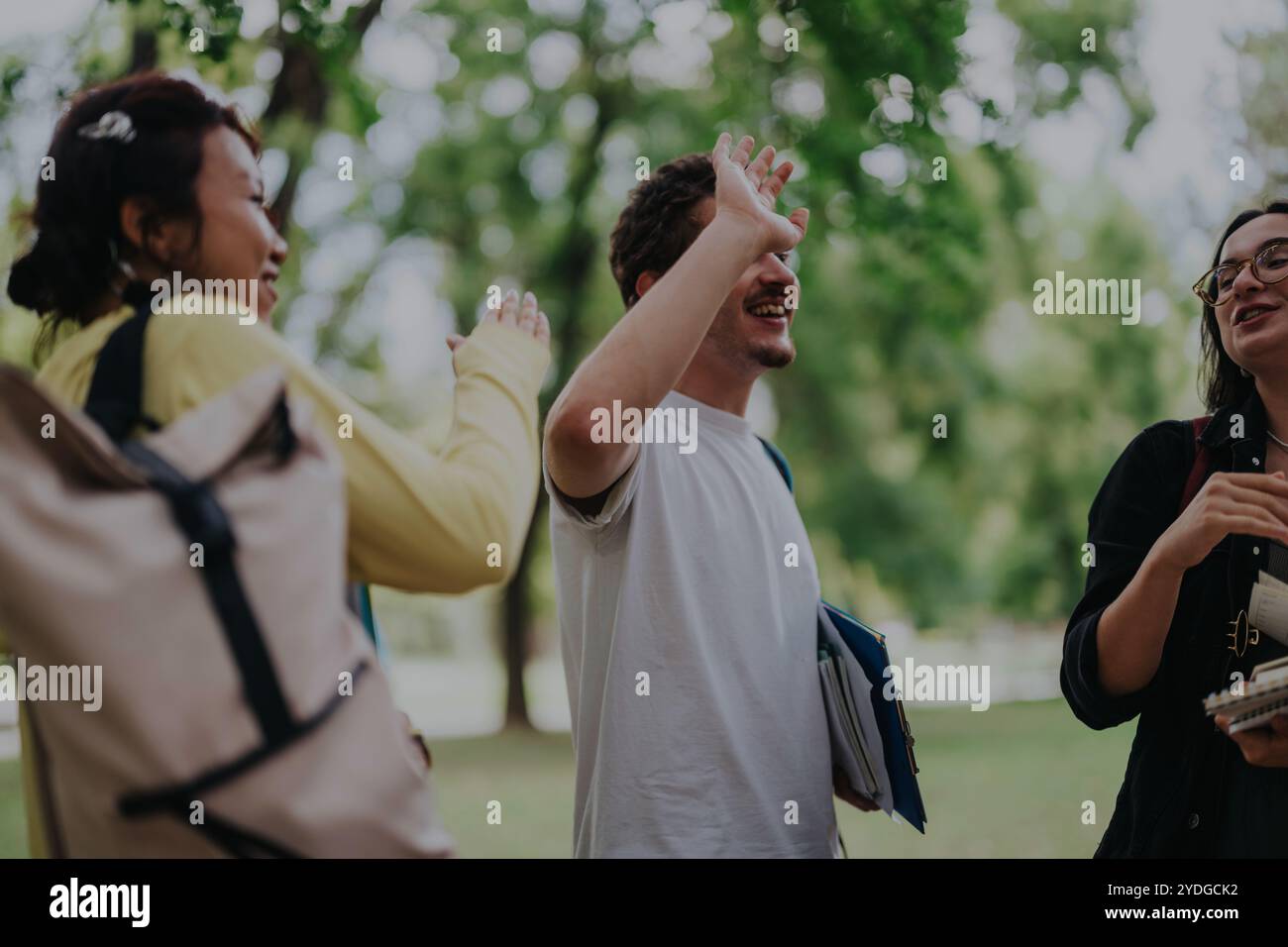 Multicultural students collaborating on assignments in a serene park setting Stock Photo