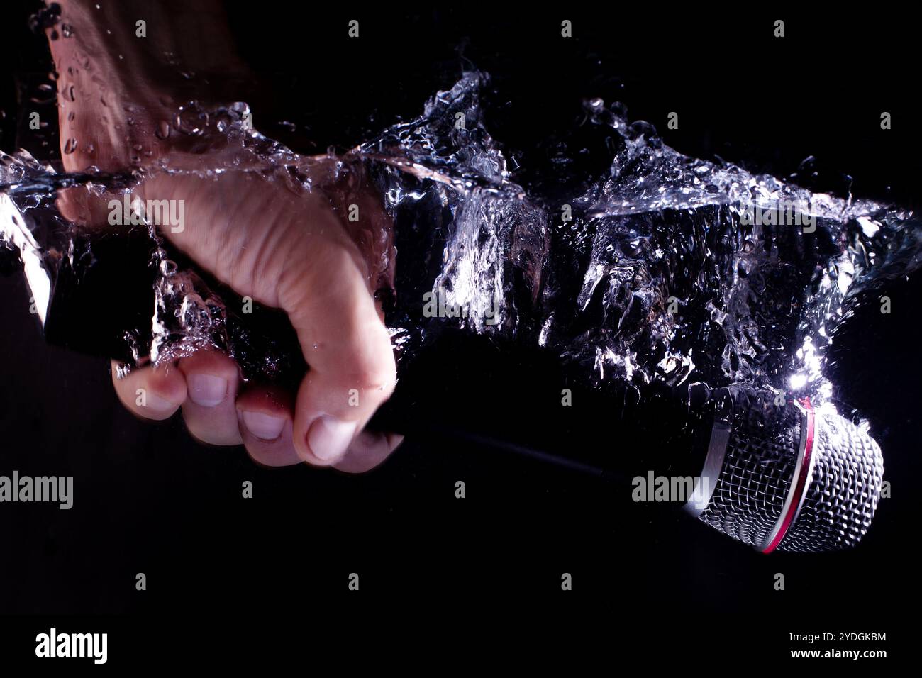 Hand Holding Microphone in Splashing Water Stock Photo