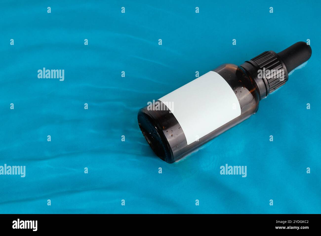 Amber Dropper Bottle with Blank Label on Blue Background Stock Photo