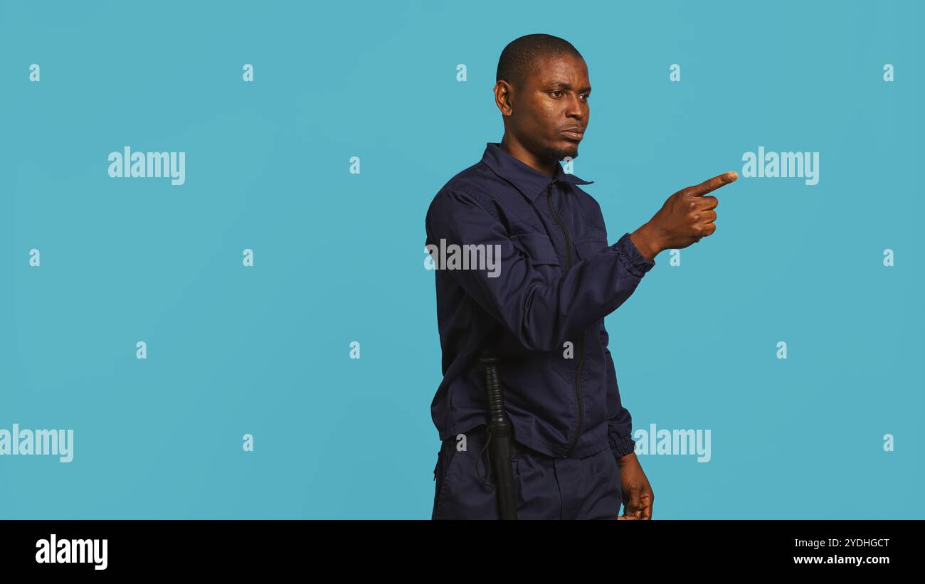 Portrait of security guard pointing finger at intruders while ...