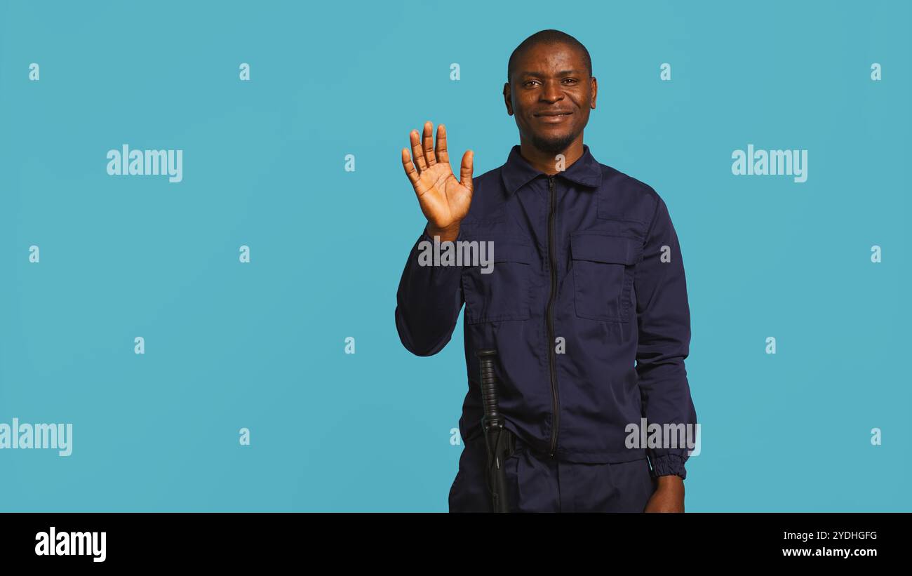 Upbeat security guard greeting people, preventing criminal activity and ...