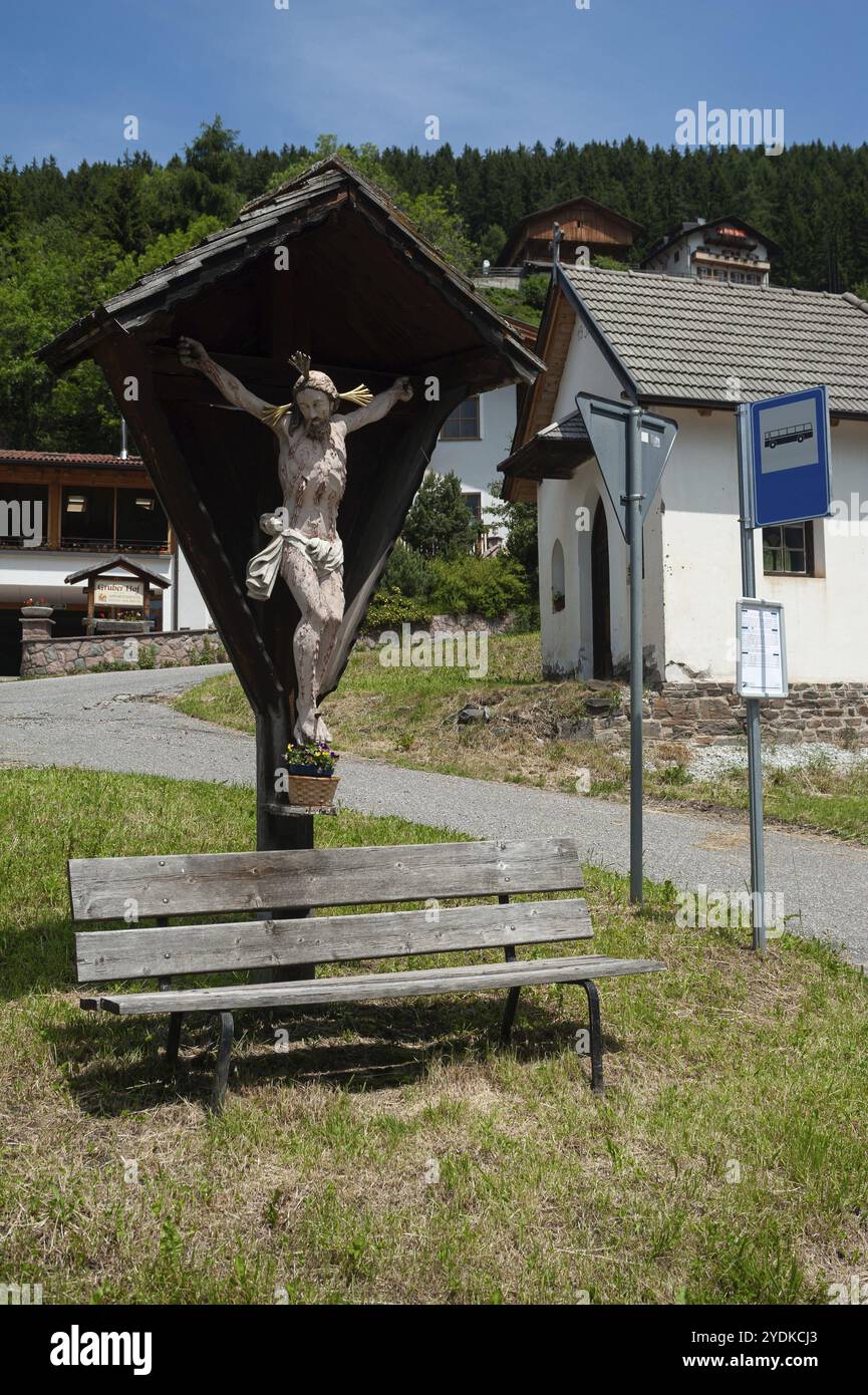 20.06.2019, Villnoess, Funes, Trentino, South Tyrol, Italy, Europe, A Jesus cross stands at a bus stop in the Villnoess valley In the background you c Stock Photo