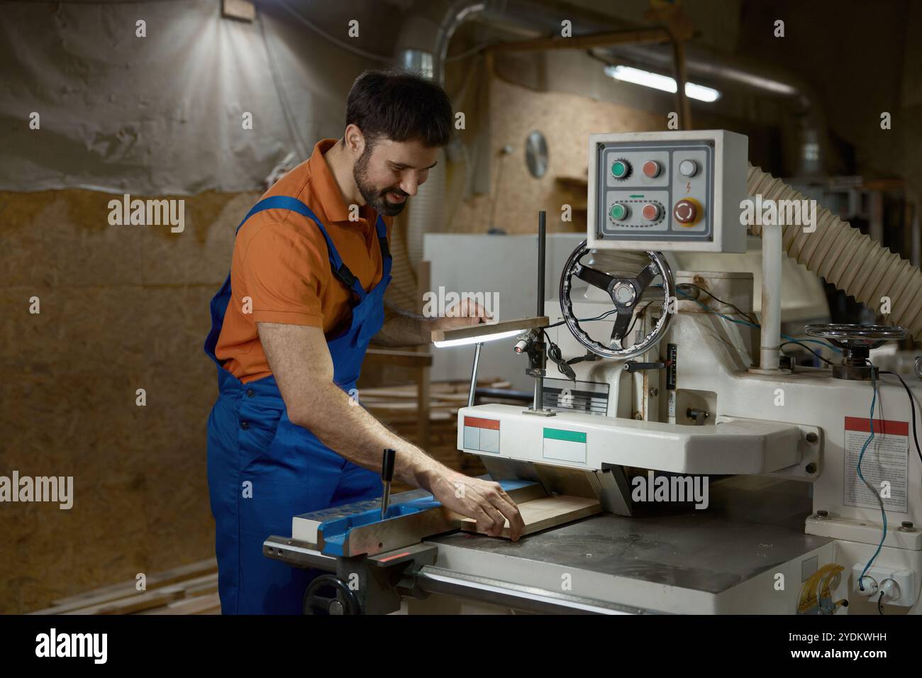 Workman using planer machine for production wooden materials specific ...